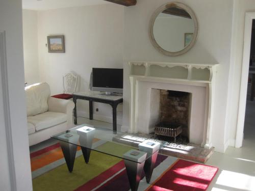 a living room with a fireplace and a table at Job's Mill Cottage in Warminster