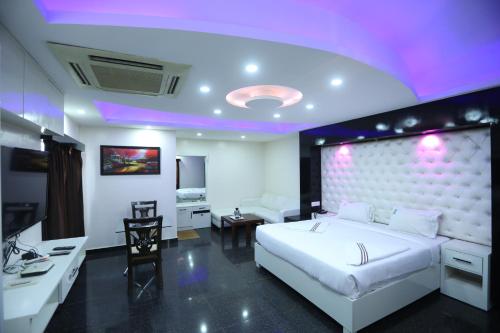a bedroom with a large white bed and a desk at Hotel RR International in Bangalore