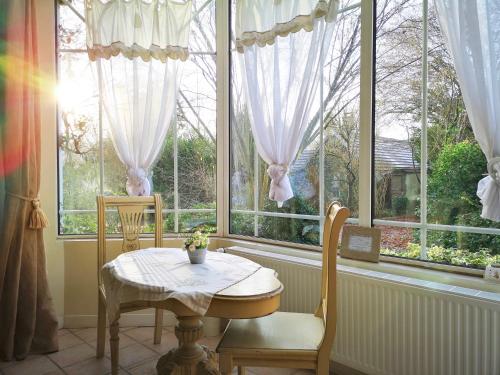 a table and chairs in a room with windows at Le Domaine des Prés du Hom in Bézu-Saint-Éloi