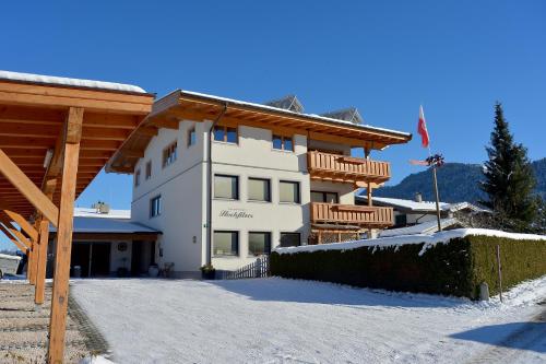 a large white building with snow on the ground at Ferienwohnungen Hochfilzer in Ellmau