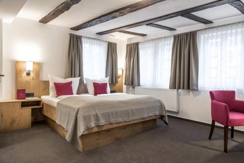 a bedroom with a large bed and a pink chair at Hotel & Restaurant Lamm in Mosbach