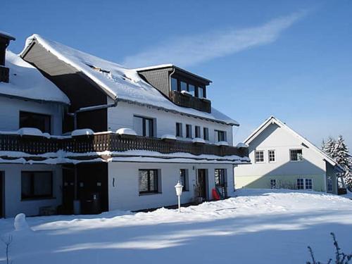 ein großes weißes Haus mit Schnee auf dem Boden in der Unterkunft Haus Panorama Sankt Andreasberg in Sankt Andreasberg