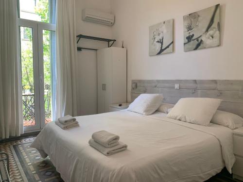 a bedroom with a white bed with towels on it at Hostal Eixample in Barcelona