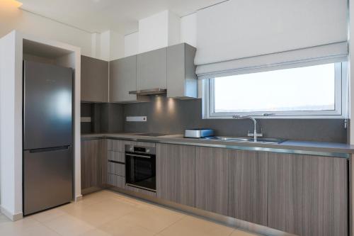 a kitchen with a stainless steel refrigerator and a window at NAPA GEM SUITES by LUXEL VILLAS in Ayia Napa