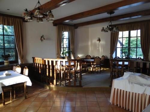 ein Esszimmer mit Tischen, Stühlen und Fenstern in der Unterkunft Villa Žerotín Penzion Bed & Breakfast in Velké Losiny