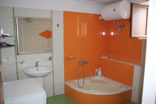 an orange tiled bathroom with a sink and a tub at Guesthouse Arjan in Berat