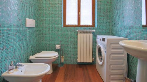 ein grün gefliestes Bad mit einem WC und einem Waschbecken in der Unterkunft Italianway - Piano delle Noci 2 in Lanzo dʼIntelvi