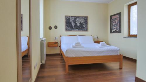 a bedroom with a bed with white sheets and wooden floors at Italianway - Piano delle Noci 2 in Lanzo dʼIntelvi