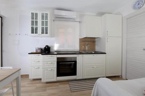a kitchen with white cabinets and a stove top oven at Appartamento Vicolo a mare, Mazzeo in Mazzeo