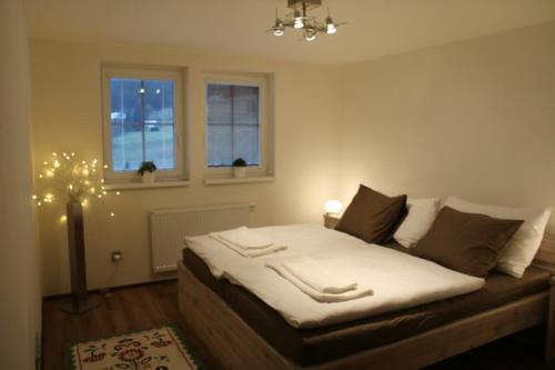 a bedroom with a bed with white sheets and two windows at Chalupa Semafor in Dolní Malá Úpa