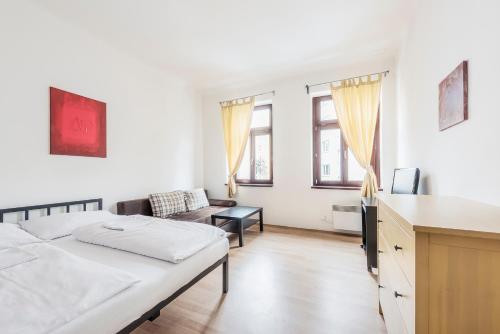 a white bedroom with a bed and a couch at Family Apartments Praha 6 in Prague