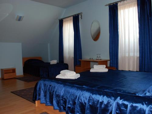 a bedroom with a blue bed and blue curtains at Pensiunea Stejarul in Sighişoara