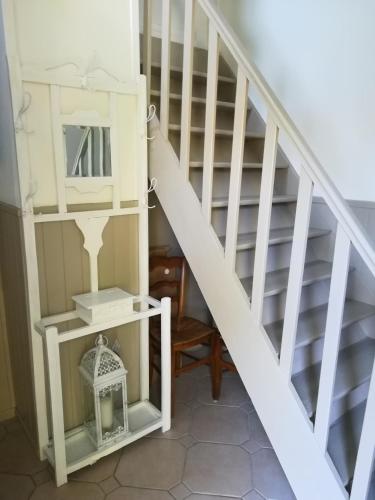 a white staircase with a chair and a table at Studio le Memagne in Lacuisine