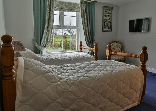 a bedroom with two beds and a window at Ford Down Farm B&B in South Molton