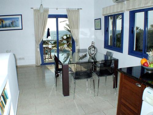 a dining room with a glass table and chairs at Kymmates Beach Front Villas in Paphos City