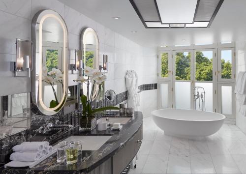 ein Badezimmer mit einer großen Badewanne und einem großen Spiegel in der Unterkunft Mandarin Oriental Hyde Park, London in London