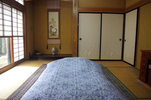 a bedroom with a large bed in a room with windows at 民宿とまとハウスTomato House in Funehiki