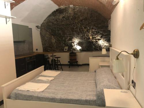 - une chambre avec un lit et un mur en pierre dans l'établissement Riomaggiore Appartamenti, à Riomaggiore