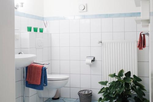 Baño blanco con aseo y lavamanos en Landhaus Woltersmühlen bei Scharbeutz, en Süsel
