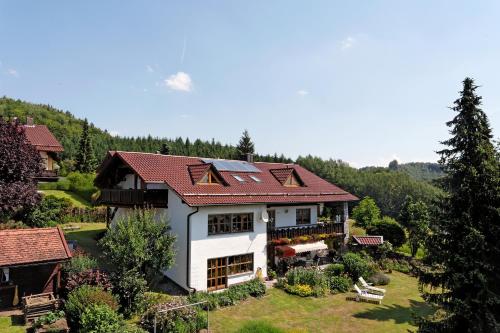 una casa con techo rojo en un patio verde en Ferienhaus Simmeth en Fürstenstein