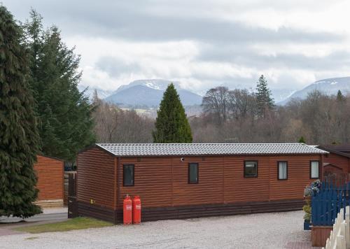 a large wooden cabin with mountains in the background at Ruapehu Lodge in Aviemore