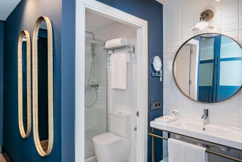 La salle de bains est pourvue de murs bleus, d'un lavabo et d'un miroir. dans l'établissement Vincci Consulado de Bilbao, à Bilbao