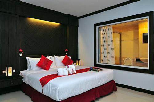 a bedroom with a large bed with red and white pillows at Patong Princess Hotel in Patong Beach