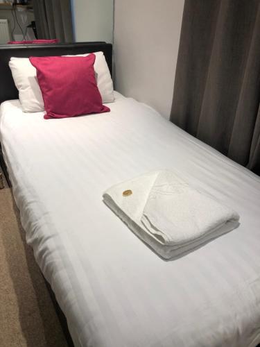 a bed with a red pillow and towels on it at Kings Hotel in Newmarket