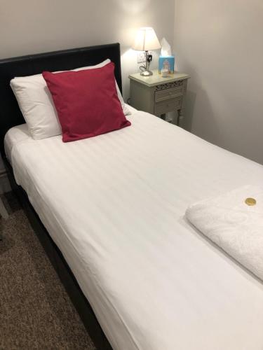 a large white bed with a red pillow on it at Kings Hotel in Newmarket