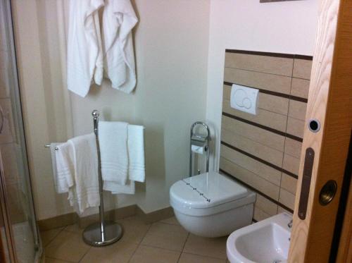 a bathroom with a toilet and a sink and towels at Elihotel in SantʼAlessio Siculo