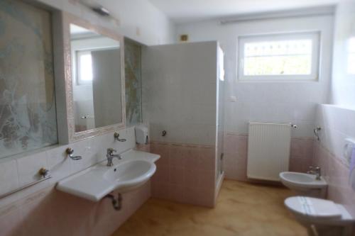 ein weißes Bad mit 2 Waschbecken und einer Dusche in der Unterkunft Admirál Villa Felnőttbarát szálláshely in Kehidakustány