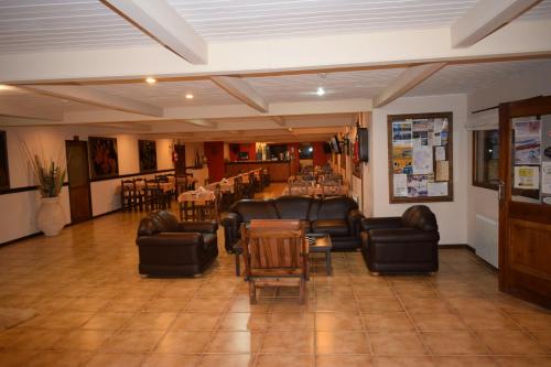 a waiting room with couches and tables and chairs at Hotel Mora in Los Antiguos
