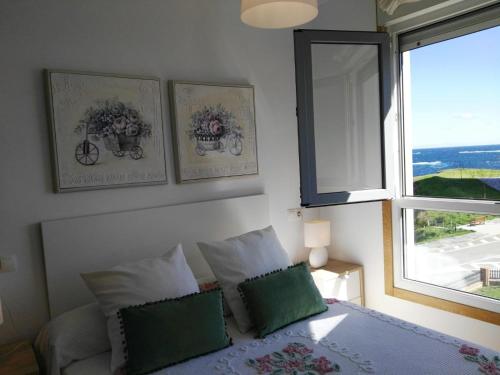 1 dormitorio con 1 cama con 2 almohadas y ventana en San Ciprián Playa y Mar by I Love Norte, en San Ciprián