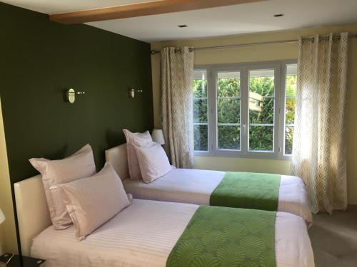 2 camas en una habitación con paredes verdes y ventana en Le Gite d'Emilie, en Entraygues-sur-Truyère