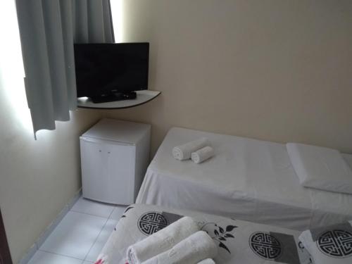 a small room with a bed and a flat screen tv at 5C Hotel in Santo Antônio de Jesus