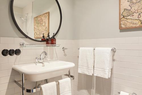 a bathroom with a sink and a mirror and towels at Fliegerdeich Hotel & Restaurant in Wilhelmshaven