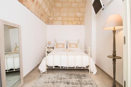 a white bedroom with a bed and a lamp at Dimora Via Vitti - Puglia Mia Apartments in Monopoli
