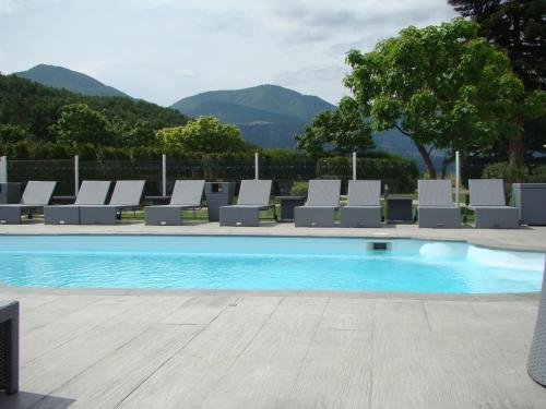 a swimming pool with lounge chairs and a mountain at Le Mas d'Estello in Tallard
