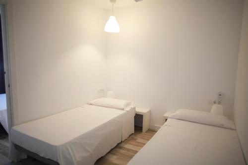 a white room with two beds and a lamp at NWT Central Station Apartments in Valencia