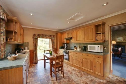 a kitchen with wooden cabinets and a table with chairs at Jock Scott Cottage in Dunkeld