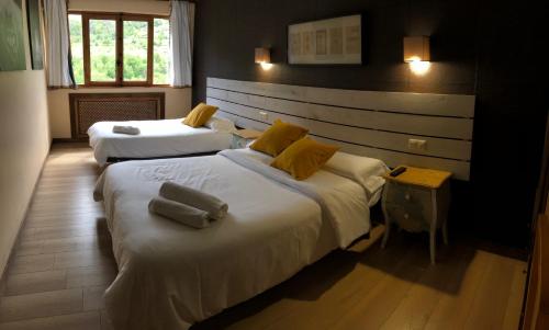 um quarto com 2 camas e almofadas amarelas em Hotel Torrecerredo em Arenas de Cabrales