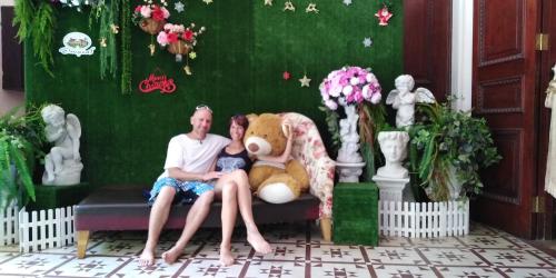 a man and woman sitting on a couch with a teddy bear at Saengcha Farm Resort in Prachin Buri