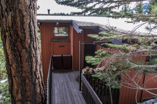 eine rote Hütte mit einem Holzsteg neben einem Baum in der Unterkunft Mammoth West #140 Condo in Mammoth Lakes