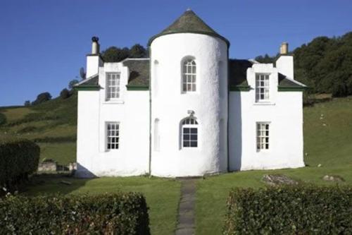 an old white house on a green field at Castle Peroch in Dunkeld