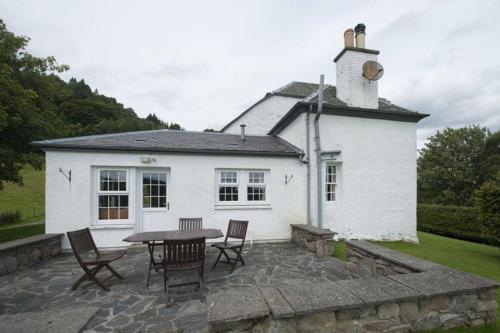 uma casa branca com uma mesa e cadeiras em frente em Castle Peroch em Dunkeld