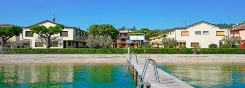 a boardwalk leading into a body of water with houses at Appartamento Romantica Pieve in Manerba del Garda