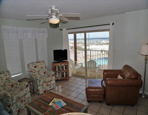 ein Wohnzimmer mit einem Sofa, Stühlen und einem TV in der Unterkunft Southern Sands 104 Condo in Gulf Shores