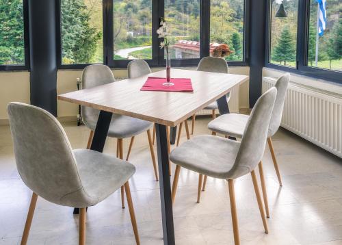a table with four chairs and a pink napkin on it at River Side Rooms in Elassona