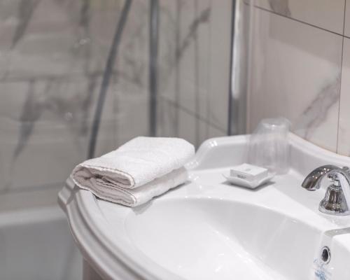 a white bathroom sink with towels and a shower at Grand Hotel Bellevue - Grand Place in Lille
