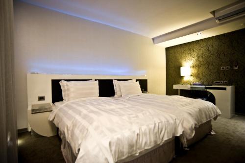 a hotel room with a large bed with white sheets at Saual Keh Hotel in Taipei
